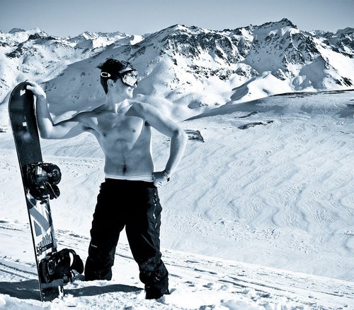 Topless male snowboarder in mountains
